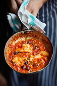 Fish with olives and tomato sauce in a pan