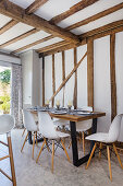 Dining area with modern chairs in open-plan kitchen with wood-beamed ceiling