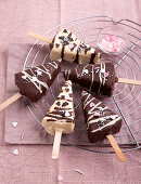 Vegan cheesecake on sticks coated with light and dark chocolate