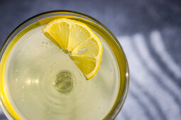 Limocello drink with lemon slice in sun light with shadows