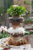 Self-made cake stands with feather wreaths; wooden discs; clay pots; eggs and radish in a pot