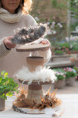 Self-made cake stands with feather wreaths; wooden discs; clay pots; eggs and radish in a pot