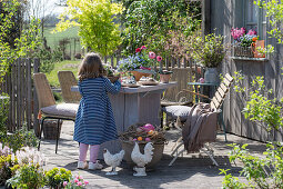 Little girl at the set table on the terrace with Easter decorations