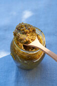 Pistachio pesto on wooden spoon and in a jar