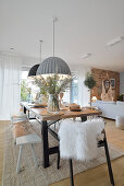 Long dining table with various seating furniture, hanging lamps above in open living space