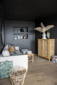 Light sofa with cushions and highboard in the living room with black walls