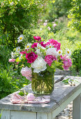 Summer bouquet of peonies, daisies and lady's mantle in a glass vase
