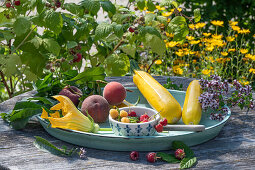 Gelbe und rote Himbeeren, Oregano, Zucchiniblüten, gelbe Zucchini und Pfirsiche aus dem Garten