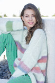 Young woman wearing a light knitted jumper with colorful stripes