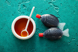Soy sauce in a small bowl and plastic fish bottles