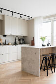 Kitchen island with bar stools in light-colored kitchen