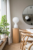 Stele with white lamp in front of window in dining area