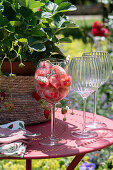 Eiswürfel mit Erdbeeren und Rosmarin im Glas auf Gartentisch