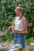 Sommerfest im Garten: Junge Frau gießt Erdbeergetränk in Glas