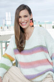 Young woman wearing a light knitted jumper with colorful stripes