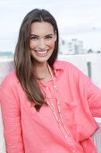 Young woman in salmon coloured shirt with pearl necklace