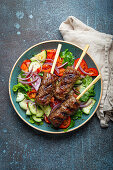 Grilled beef kebabs served with fresh vegetables salad (Traditional Middle Eastern and Turkish dish)