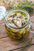 Pickled oysters in olive oil with herbs and spices in a jar