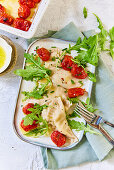 Schlutzkrapfen garnished with tomatoes and rocket salad