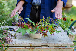 Herbstliches Blumengesteck arrangieren mit Heidekraut (Erika), Himbeerzweig und Heidelbeeren