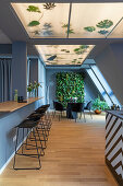 Long counter with black bar stools, small dining area and vertical garden in the background