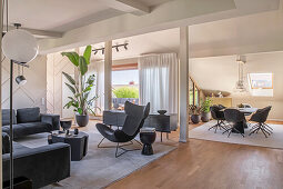 Elegant living room with dark seating furniture, dining area in the background