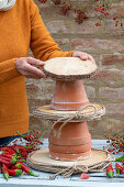 Herbstliche Etagere aus Tontöpfen, Holzscheiben und Hagebuttenzweigen basteln