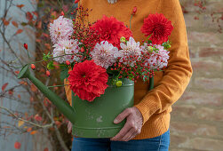 Autumn bouquet of dahlias and rose hip branches in watering can