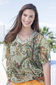 A young woman wearing a colorful, airy summer blouse