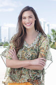 A young woman wearing a colorful, airy summer blouse