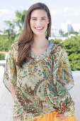 A young woman wearing a colorful, airy summer blouse