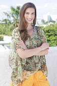 A young woman wearing a colorful, airy summer blouse and yellow shorts