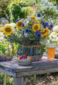 Summer bouquet with sunflowers and globe thistles on wooden table in the garden