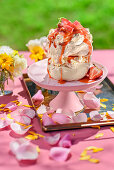 Meringue with rhubarb cream on pink pastry stand on outdoor table
