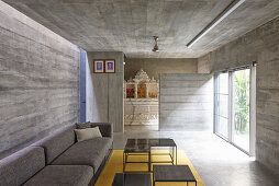 Sofa with a table set in a seating area with terrace access in a concrete house