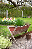 DIY-Pflanzkasten aus Recyclingholz im Frühlingsgarten mit Blumenbeet