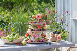 Etagere mit Rosenblüten, Strohblumen, Duftwicken, Hagebutten und Herbstfrüchten als Tischdekoration