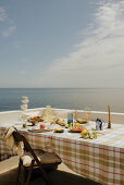 Set table with checkered tablecloth on terrace with sea view