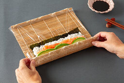 Making maki sushi with salmon and avocado