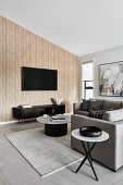 Modern, neutral toned open-plan living room with columned coffee table and cream carpeting