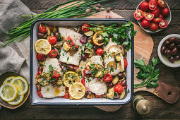 Roasted fish fillets with tomatoes, zucchini, olives and lemon
