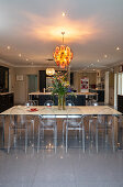 Dining table with transparent chairs and central chandelier