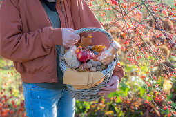 Frau mit Picknickkorb unter Zierapfelbaum im Herbstgarten