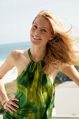 Blonde woman in green halter dress by the sea