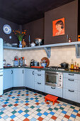 Küche mit blau-grauen Unterschränken, bunten Bodenfliesen und braunen Wänden