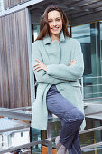 Young brunette woman in blue pants and light blue coat