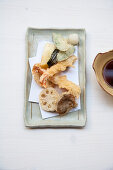 Tempura von Garnelen, Zuckerschoten, Pilz und Lotuswurzel, dazu Sojasauce (Japan)