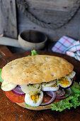 Focaccia sandwich with eggs, tomatoes and onions