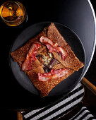 Galette with raclette cheese, red onions and crispy bacon