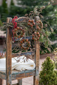 Winterlicher Kranz aus Haselnüssen und Kiefernzweigen an Holzstuhl hängend